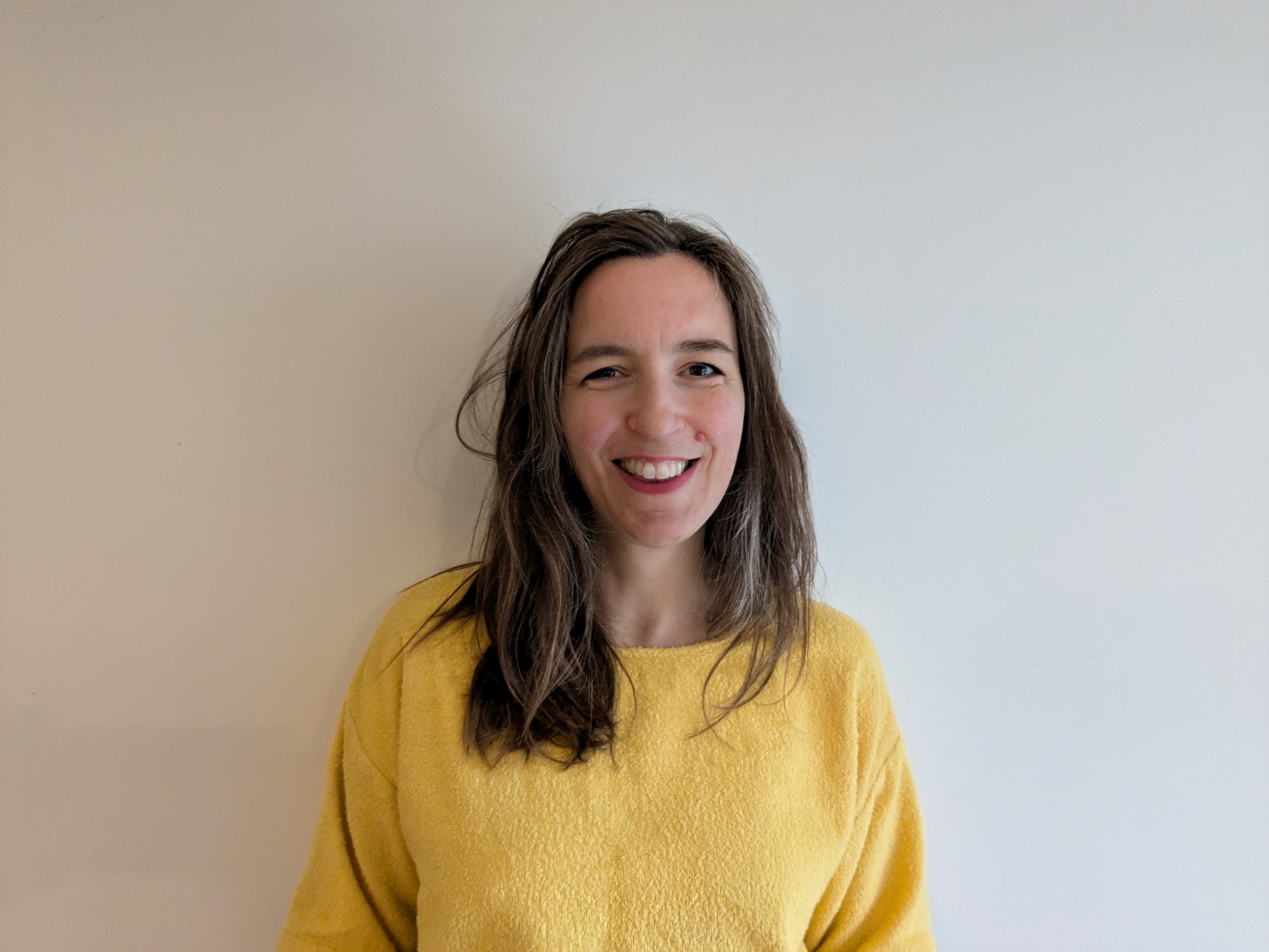 Nichola Smalley is wearing a yellow jumper and smiling at the camera.